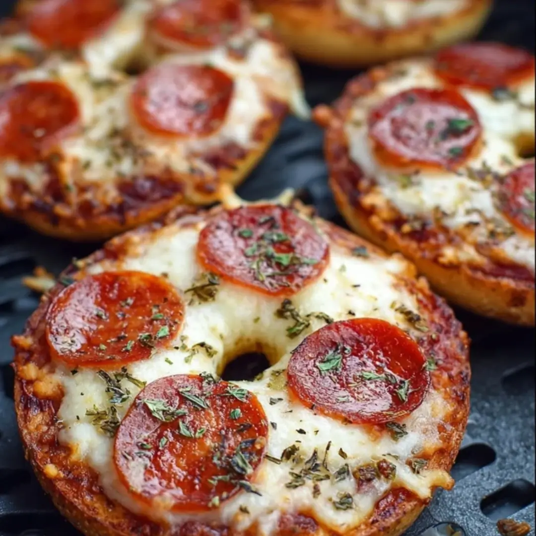 Hot air fryer bagel pizzas topped with melted mozzarella, cherry tomatoes, bell peppers, and fresh basil.