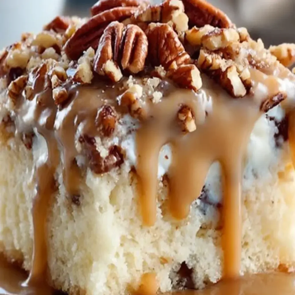 inch Butter Pecan Praline Poke Cake topped with a thick layer of white whipped topping, toasted pecans, and a rich caramel drizzle.
