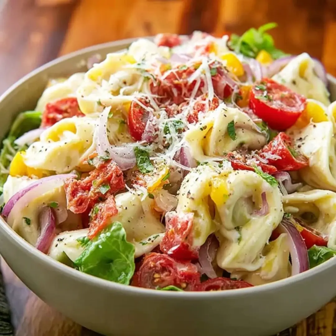 Creamy Fresh Grinder Tortellini Salad with cheese tortellini, cherry tomatoes, red onion, provolone, and a zesty dressing in a bowl.
