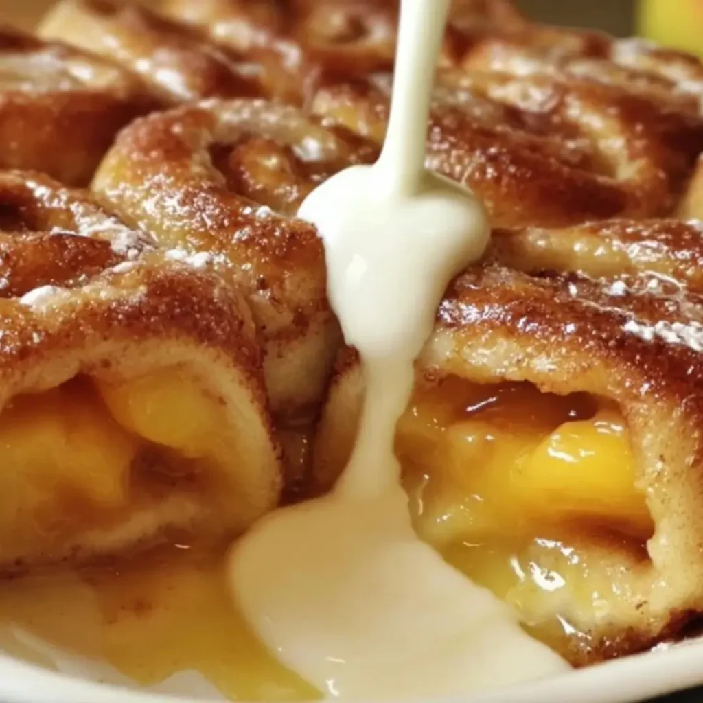 Close-up of warm, freshly baked Peach Cheesecake Cinnamon Rolls drizzled with a thick, creamy cream cheese glaze.
