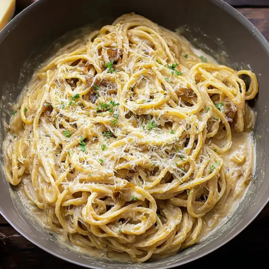Creamy French Onion and Browned Butter Pasta dish topped with grated Parmesan cheese and fresh parsley in a gray bowl.